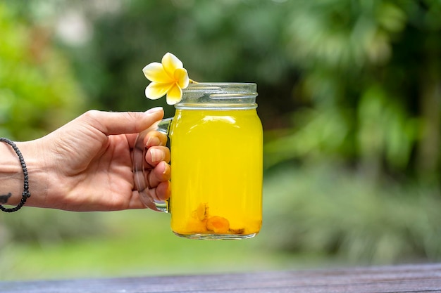 Bebida tônica energética com limão de gengibre açafrão e mel em fundo de natureza de caneca de vidro close-up O conceito de alimentação saudável