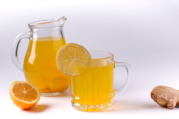 Bebida tonificante casera con limón, jengibre, miel y cúrcuma sobre una superficie blanca