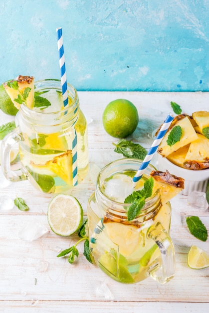 Bebida tropical Mojito de piña o limonada con lima fresca y menta fondo azul claro