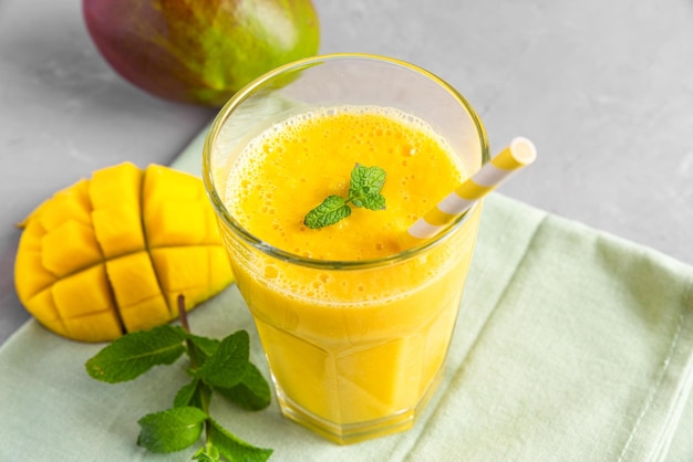 Bebida tropical de verano Batido de mango fresco en un vaso con pajita y menta