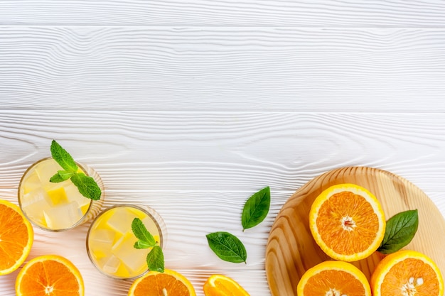 Bebida de verano de naranja con hielo en madera blanca