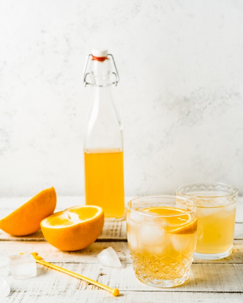 Bebida de verano naranja, naranjas frescas sobre fondo blanco. Imagen vertical