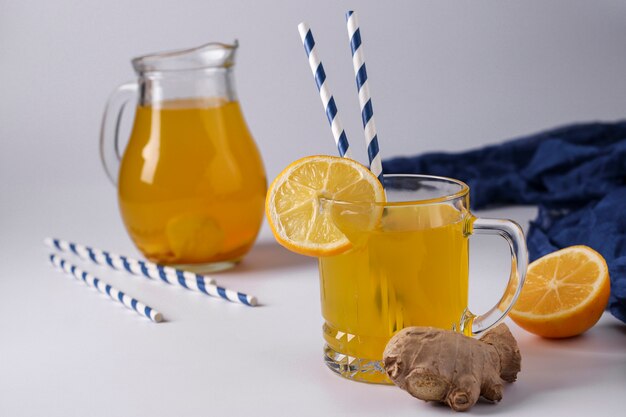 Bebida vigorizante casera con limón, jengibre, miel y cúrcuma sobre una superficie blanca, orientación horizontal, primer plano