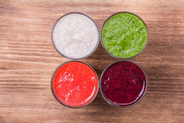 Bebidas de aguacate fresco, fresa, frambuesa y plátano en una mesa de madera, cócteles de proteínas variados con frutas frescas, concepto de batido.