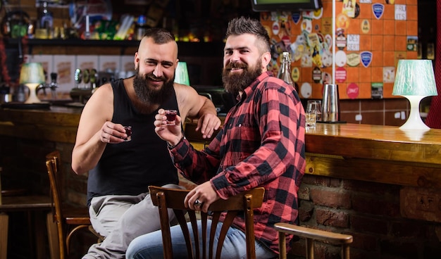 Bebidas alcohólicas fuertes Viernes relajarse en el pub Amigos relajándose en el pub Concepto de saludo Hipster brutal hombre barbudo bebiendo alcohol con un amigo en el mostrador del bar Hombres borrachos relajándose en el pub divirtiéndose