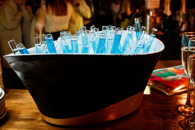 Bebidas azules en un vaso de precipitados dentro de un cubo con hielo