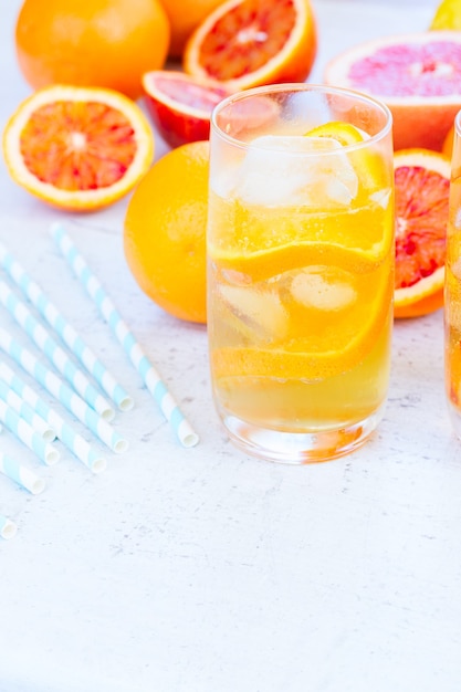 Bebidas cítricas refrescantes de verano en vaso con hielo en el cuadro blanco