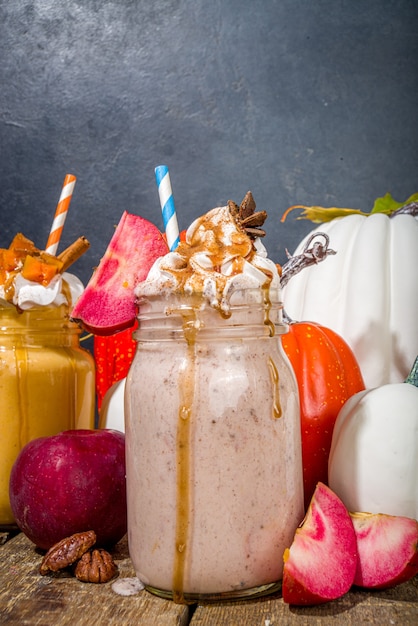 Bebidas de smoothie de torta de maçã, abóbora e noz-pecã. Conjunto de coquetéis com sabor de bolo assado no outono tradicional, em um espaço de cópia de fundo escuro de madeira