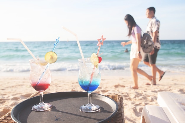 Bebidas de verão com amantes caminhando na praia