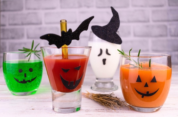 Bebidas diferentes para o Halloween em copos decorados com rostos assustadores.