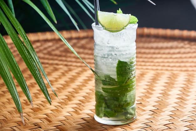 Bebidas frías de verano con jugo fresco, menta, hielo en una mesa de mimbre con hojas