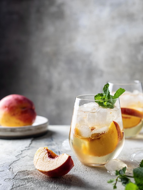 Bebidas geladas de verão limonada gelada de pêssego caseira com hortelã no plano de fundo texturizado com espaço de texto