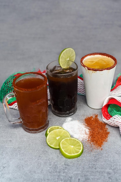 Bebidas mexicanas Charro Negro, Jarrito, Cerveza roja em uma mesa cinza com sal, pimenta e limão