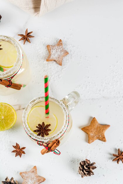 Bebidas de otoño e invierno. Bebida navideña. Cóctel festivo de bolas de nieve con jugo de limón, canela, licor, azúcar y estrellas de anís. En la mesa blanca con decoración navideña, vista superior