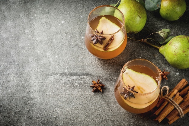 Bebidas de otoño Vino caliente Otoño tradicional picante cóctel con pera, sidra y jarabe de chocolate, con canela, anís, azúcar moreno. En la mesa de piedra negra. Copia espacio vista superior