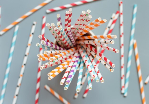 Foto bebidas de papel a rayas y puntos en un vaso con fondo gris desde arriba