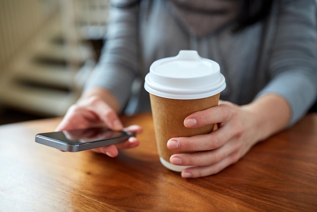 bebidas, pessoas, tecnologia e conceito de estilo de vida - close de mulher com smartphone e café na mesa do café