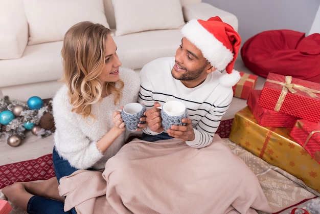 Bebidas quentes. agradável casal feliz sentado junto e segurando suas xícaras enquanto tomam chá