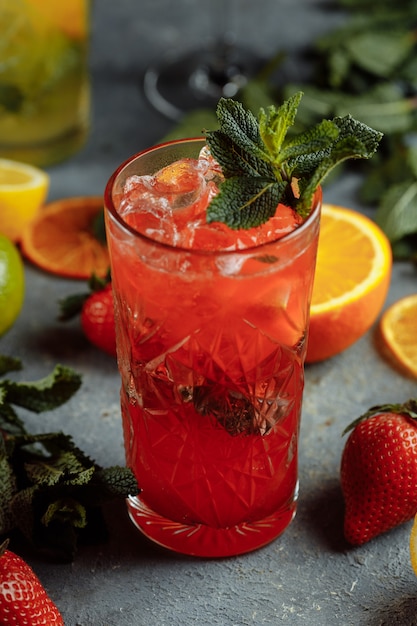 Bebidas refrescantes coloridas para o verão, suco de limonada de morango gelado com cubos de gelo nos copos enfeitados com limões frescos fatiados