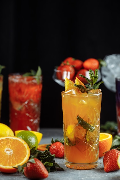 Bebidas refrescantes coloridas para o verão, suco de limonada de morango gelado com cubos de gelo nos copos enfeitados com limões frescos fatiados.