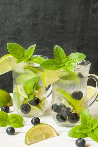 Bebidas refrescantes de verano con limonada o cóctel de mojito con menta fresca de limón y hielo de arándanos.