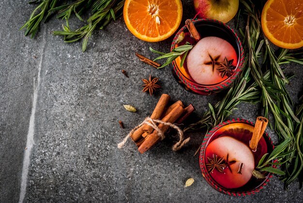 Bebidas tradicionais de inverno e outono. Cocktails de Natal e ação de graças. Vinho quente com laranja, maçã, alecrim, canela e especiarias