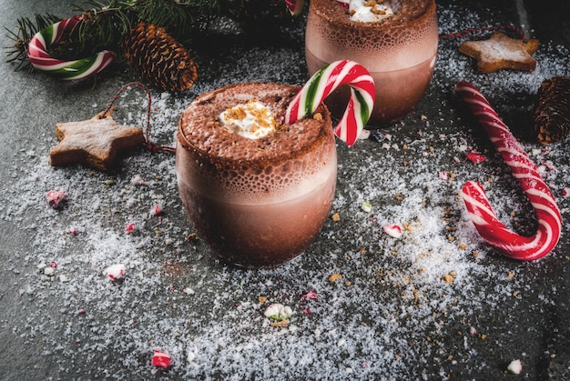 Bebidas tradicionales de navidad. Cóctel del Polo Norte con dulces de caña de azúcar, menta, chocolate caliente o cacao, jengibre y leche. Oscuro, con decoración navideña, copyspace