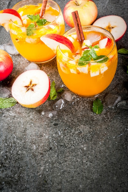 Bebidas tradicionales de otoño, cócteles de mojito de sidra de manzana con menta, canela y hielo. En la mesa de piedra negra, copie el espacio