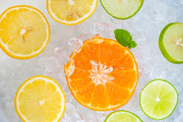 Bebidas de verano refrescantes de bebidas frías, fruta fresca en un cubo de hielo, té cóctel con mojito, limón, lima, naranja