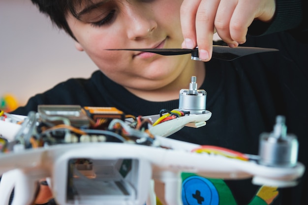 Beca de Física. Un joven inventor pone una hélice en un dron. Clases extracurriculares de física en el laboratorio de casa.