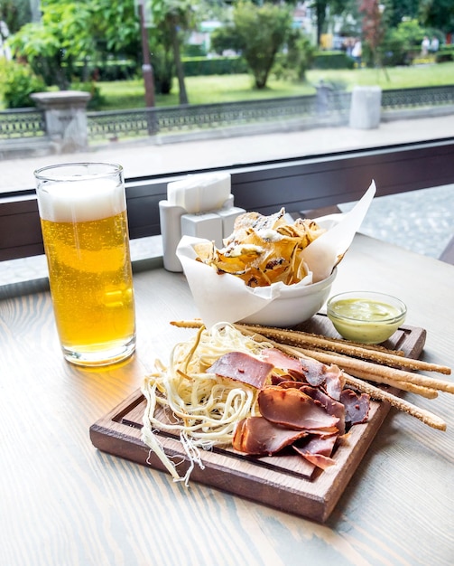 Becher Bier mit salzigen Snacks auf dem Tisch an der Bar