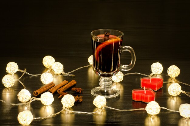 Becher Glühwein mit Gewürzen und heller Girlande