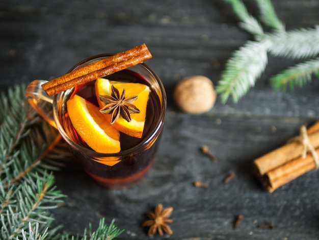 Becher heißer Glühwein mit Zimt und Gewürzen auf hölzerner Tabelle