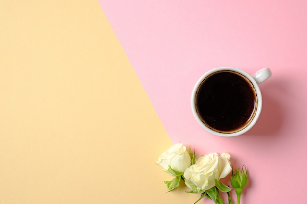 Becher Kaffee und Blumenstrauß von Rosenblumen auf Pastellhintergrund.