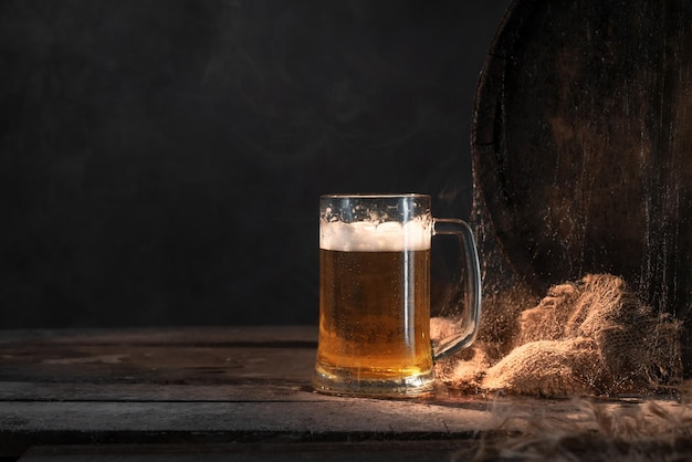 Becher mit frischem hellem Bier mit Schaum auf hölzernem Vintage-Hintergrund mit FassÑŽ Alter Weinkeller oder Pub