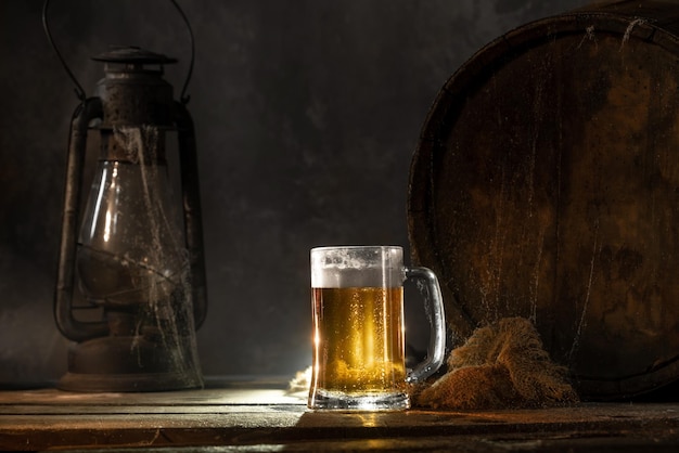 Becher mit frischem hellem Bier mit Schaum auf hölzernem Vintage-Hintergrund mit FassÑŽ Alter Weinkeller oder Pub