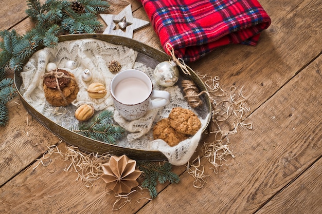 Becher mit Getränk und Kekse mit Weihnachtsdekoration