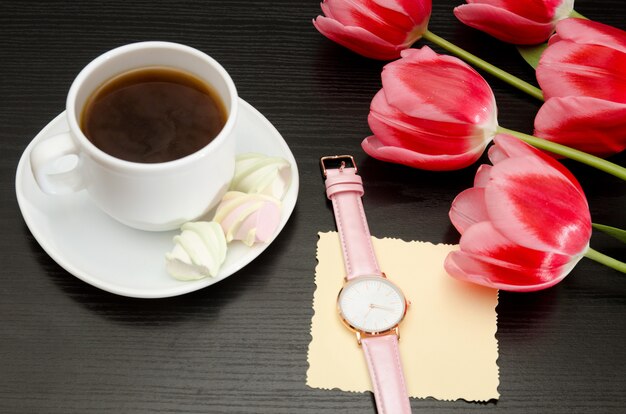 Becher mit Kaffee und Eibisch, Netzpostkarte, Uhr, rosa Tulpen.