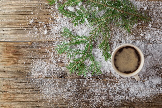 Becher Tee und grüner Weihnachtsbaum auf Schnee auf Holztisch