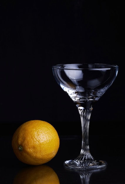Becherglas mit Gin Tonic Cocktail und Zitrone auf isoliertem Schwarz