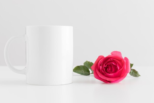 Foto bechermodell mit einer rosa rose auf einem weißen tisch