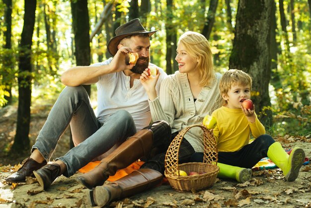 Bedeutung der glücklichen Familie Vereint mit der Natur Familientag Konzept Glückliche Familie mit Kind Junge entspannend beim Wandern im Wald Mutter Vater und kleiner Sohn Picknick Landhausstil Familie Picknick in der Natur