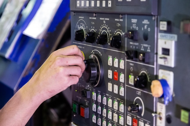 Bediener handdrehender Jog-Griff auf CNC-Maschinensteuertafel Nahaufnahme mit selektivem Fokus und Unschärfe