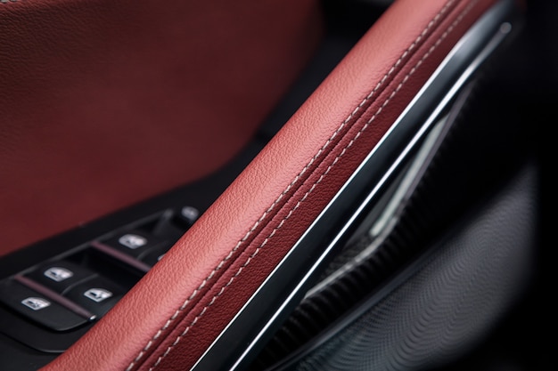 Bedienfeld mit Chromgriff an der Autotür, übliches schwarzes und rotes Echtleder in einem Neuwagen. Armlehne im Luxusauto