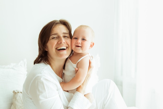 Foto bedingungslose liebe. porträt einer jungen frau, die sich mit ihrem neugeborenen baby verbindet, zu hause auf dem bett sitzt, freier platz