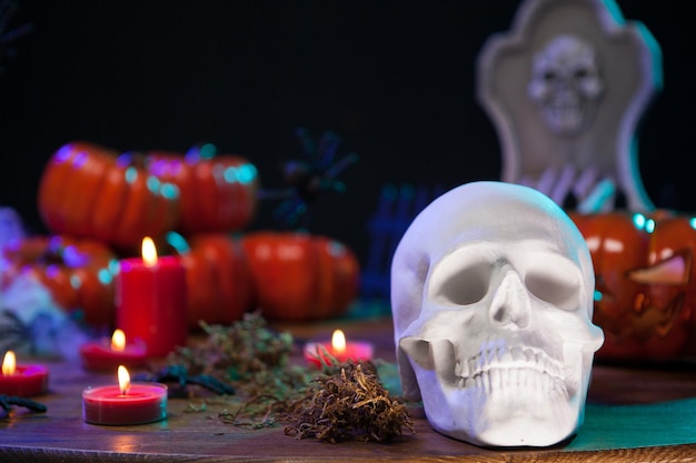 Bedrohlicher Schädel für Halloween-Party, der auf einem Holztisch mit gruseligem Kürbis sitzt. Spukender menschlicher Schädel.