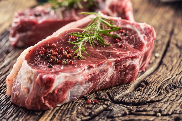 Beef Rib Eye Steak mit Salzpfeffer und Rosmarin auf Holztisch.