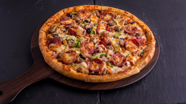 Beef Supreme Pizza isoliert auf Schneidebrett Draufsicht auf dunklem Hintergrund italienisches Fast Food