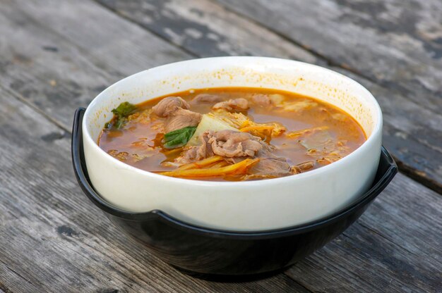 Beef Tomyam sopa azeda salgada picante Comida tradicional asiática em uma tigela branca sobre uma velha mesa de madeira