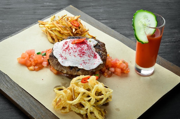 Beefsteak Kalb mit pochiertem Ei und Tomatensaft Auf einem hölzernen Hintergrund Ansicht von oben Freier Platz für Ihren Text